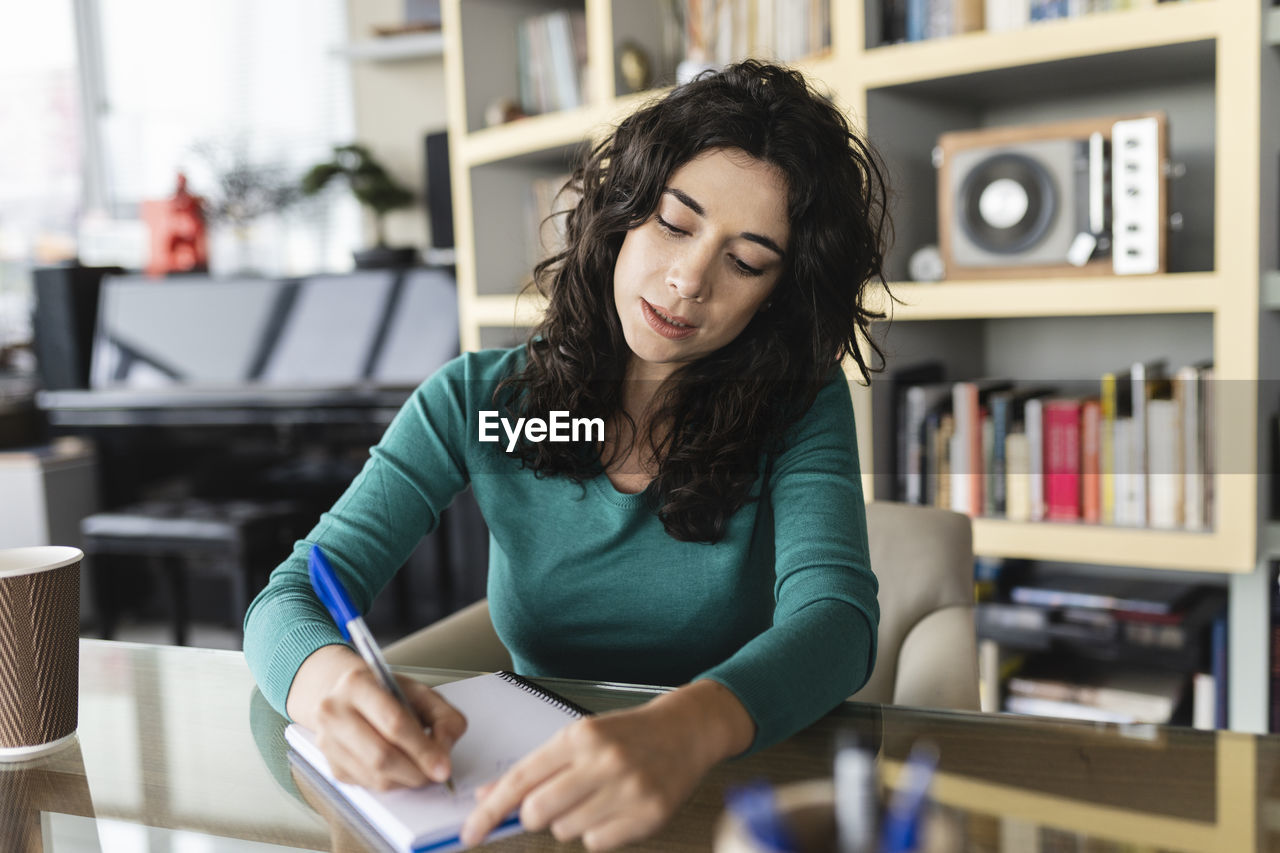 Businesswoman writing in diary at office