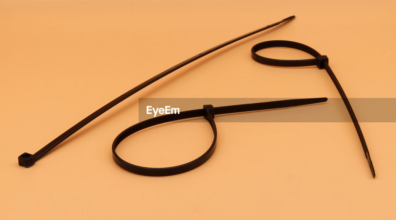 Black cable ties isolated on orange background. plastic tie wraps.