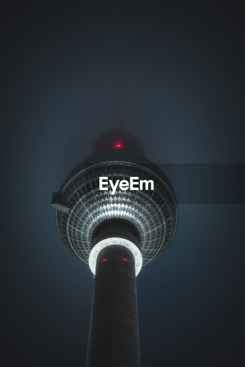 Low angle view of illuminated communications tower against sky at night