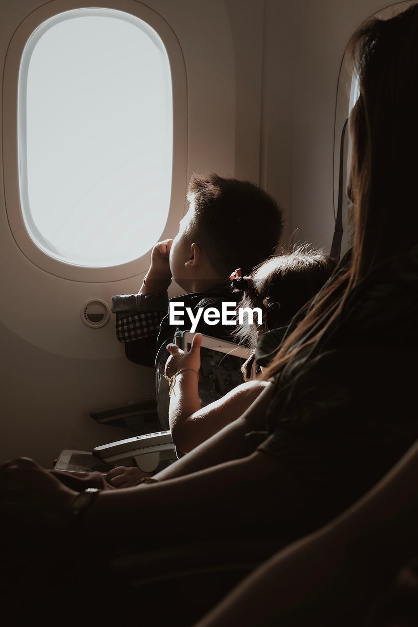 SIDE VIEW OF GIRL SITTING AT AIRPLANE