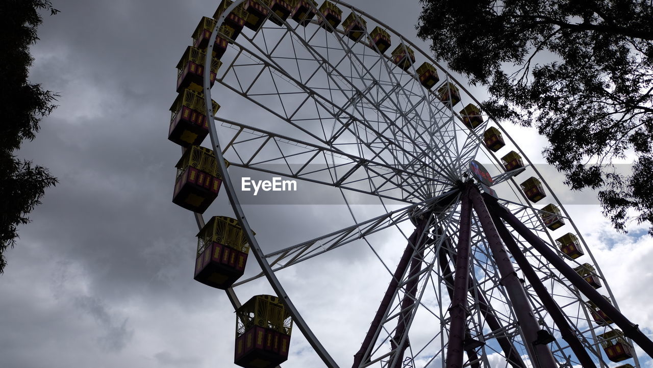 LOW ANGLE VIEW OF FERRIS WHEEL BY TREE AGAINST SKY