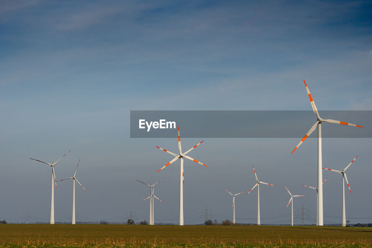 WIND TURBINES ON FIELD AGAINST BLUE SKY