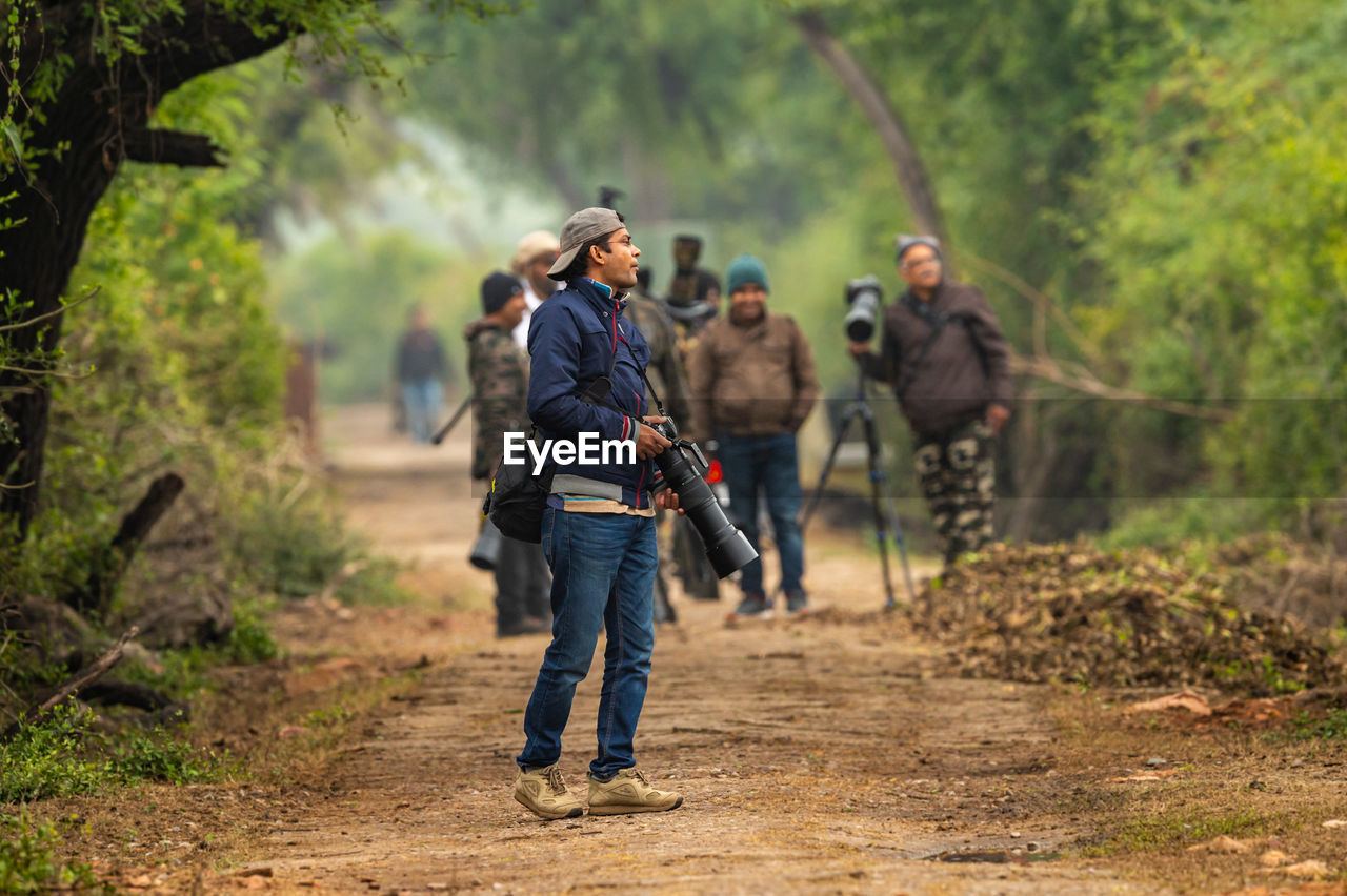 REAR VIEW OF PEOPLE WALKING ON STREET AMIDST TREES