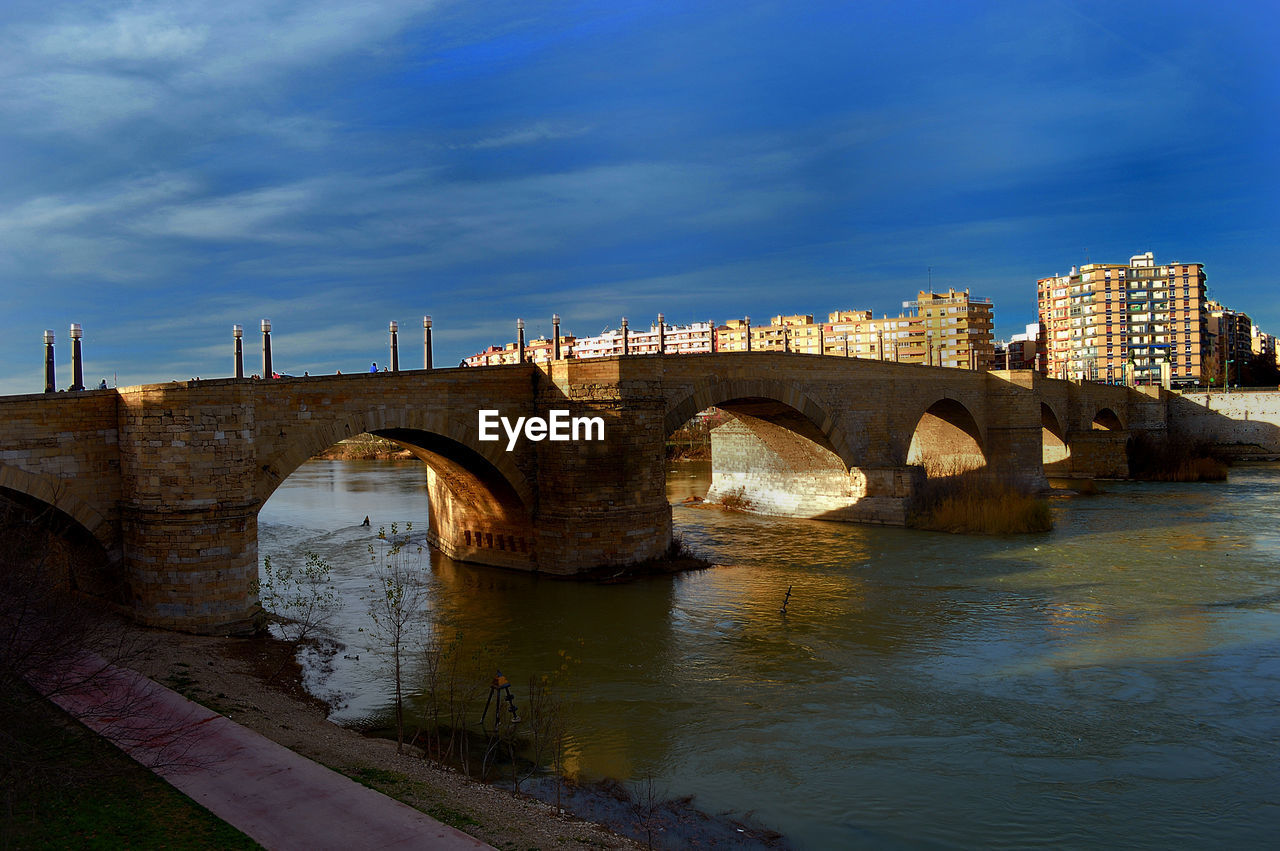 Arch bridge over river against sky