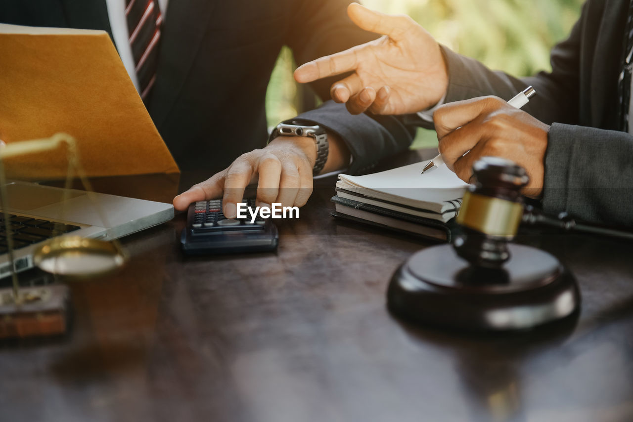 midsection of lawyer using calculator at desk