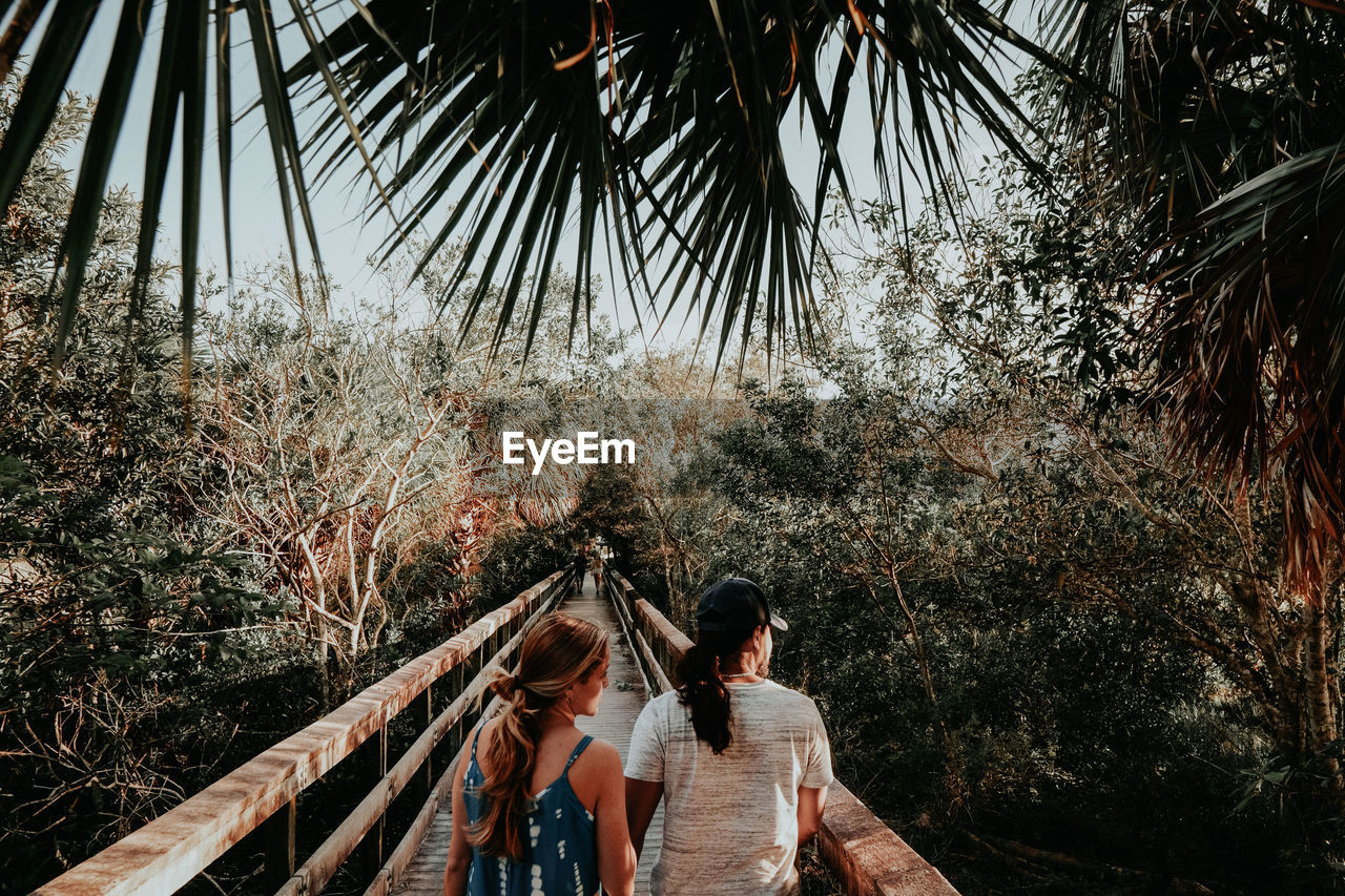 REAR VIEW OF COUPLE STANDING ON RAILING