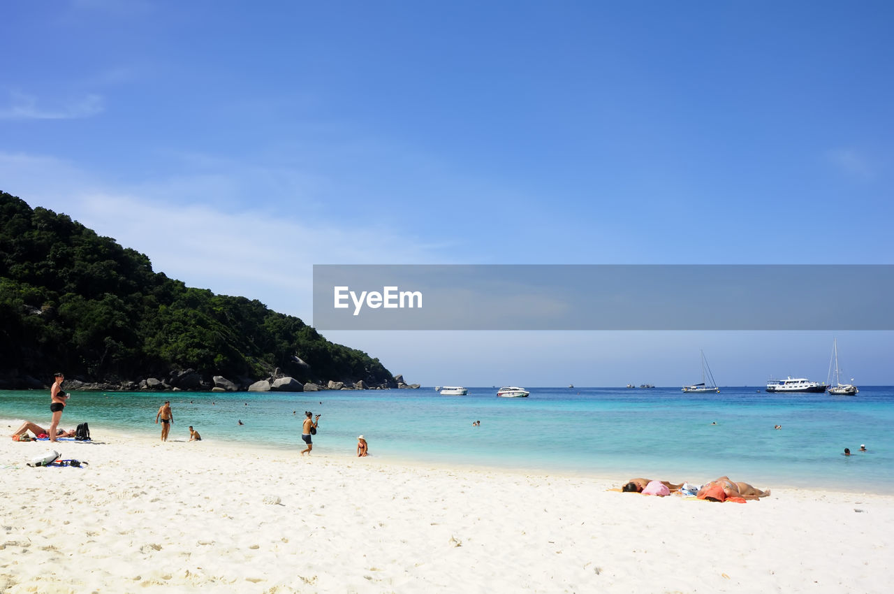 VIEW OF PEOPLE ON BEACH AGAINST BLUE SKY