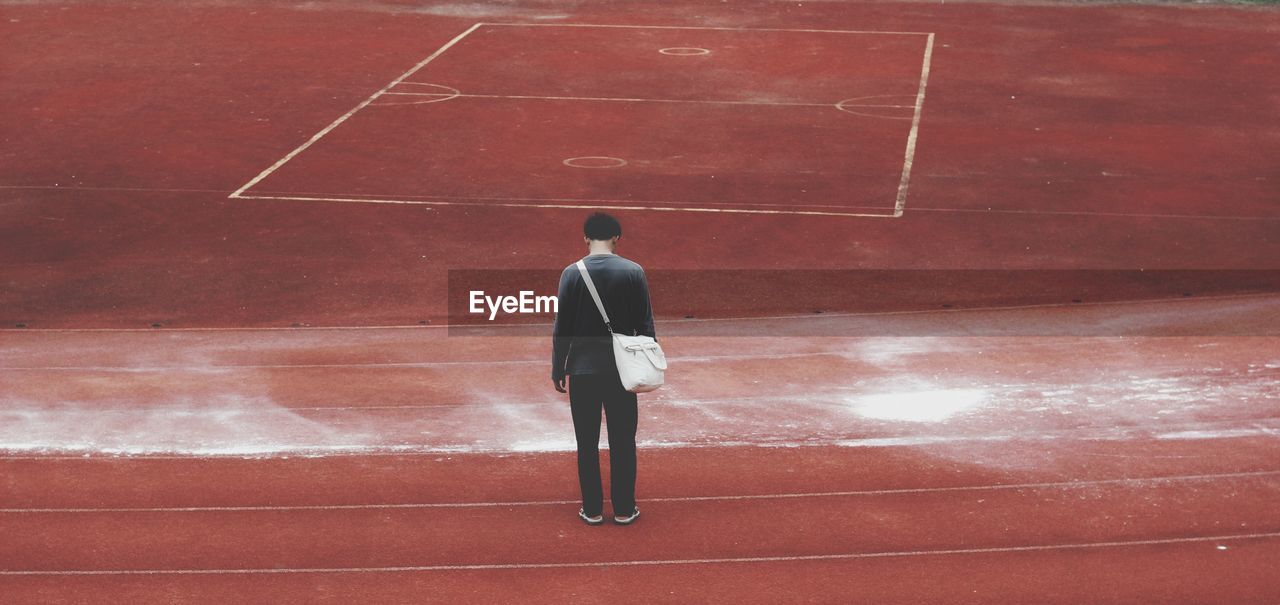 Rear view of man standing on sports track