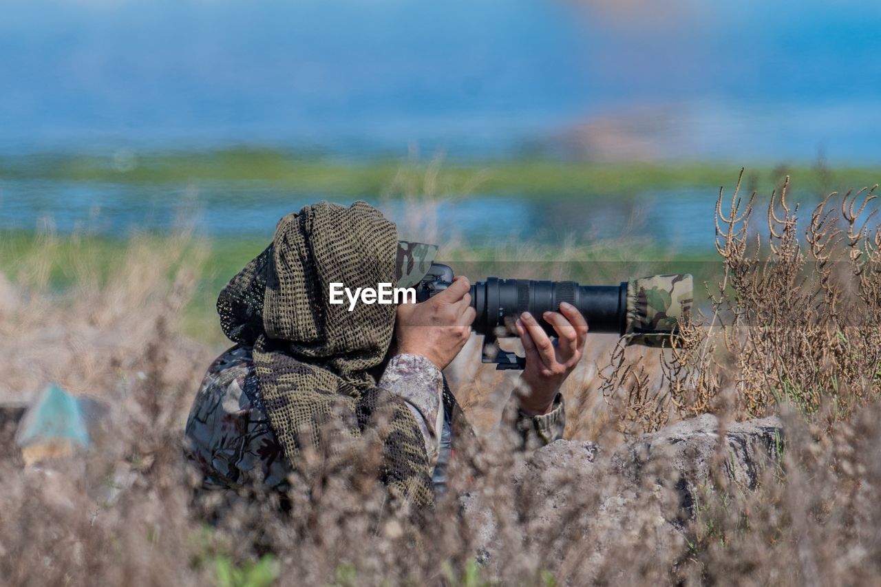 Man photographing on land against lake