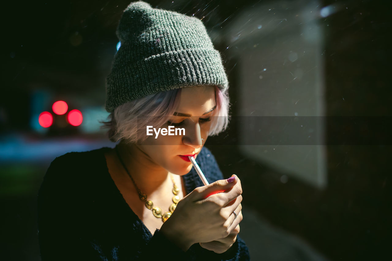 Close-up of young woman lighting cigarette