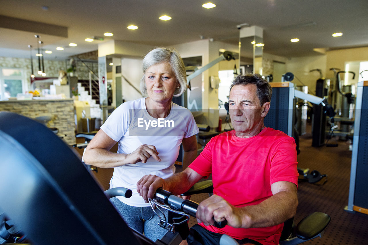 Senior man and mature woman working out in fitness gym