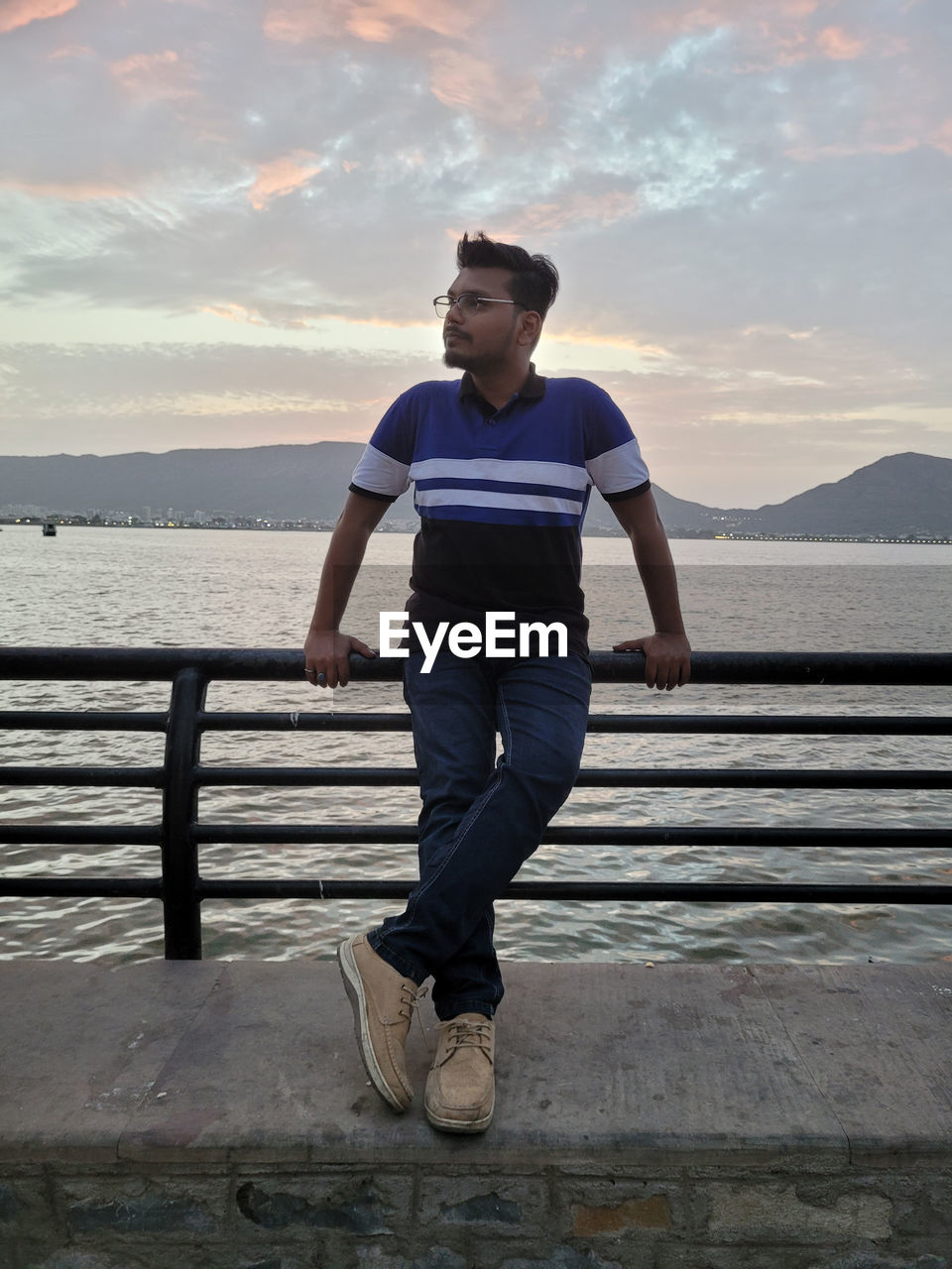 one person, water, sky, full length, sea, adult, lifestyles, blue, nature, cloud, leisure activity, men, casual clothing, young adult, railing, sunset, beach, front view, exercising, day, architecture, standing, vacation, sports, relaxation, footwear, outdoors, running, looking, land, beauty in nature, clothing, ocean, sunlight, motion, scenics - nature, looking away, person, vitality, pier, jogging, tranquility