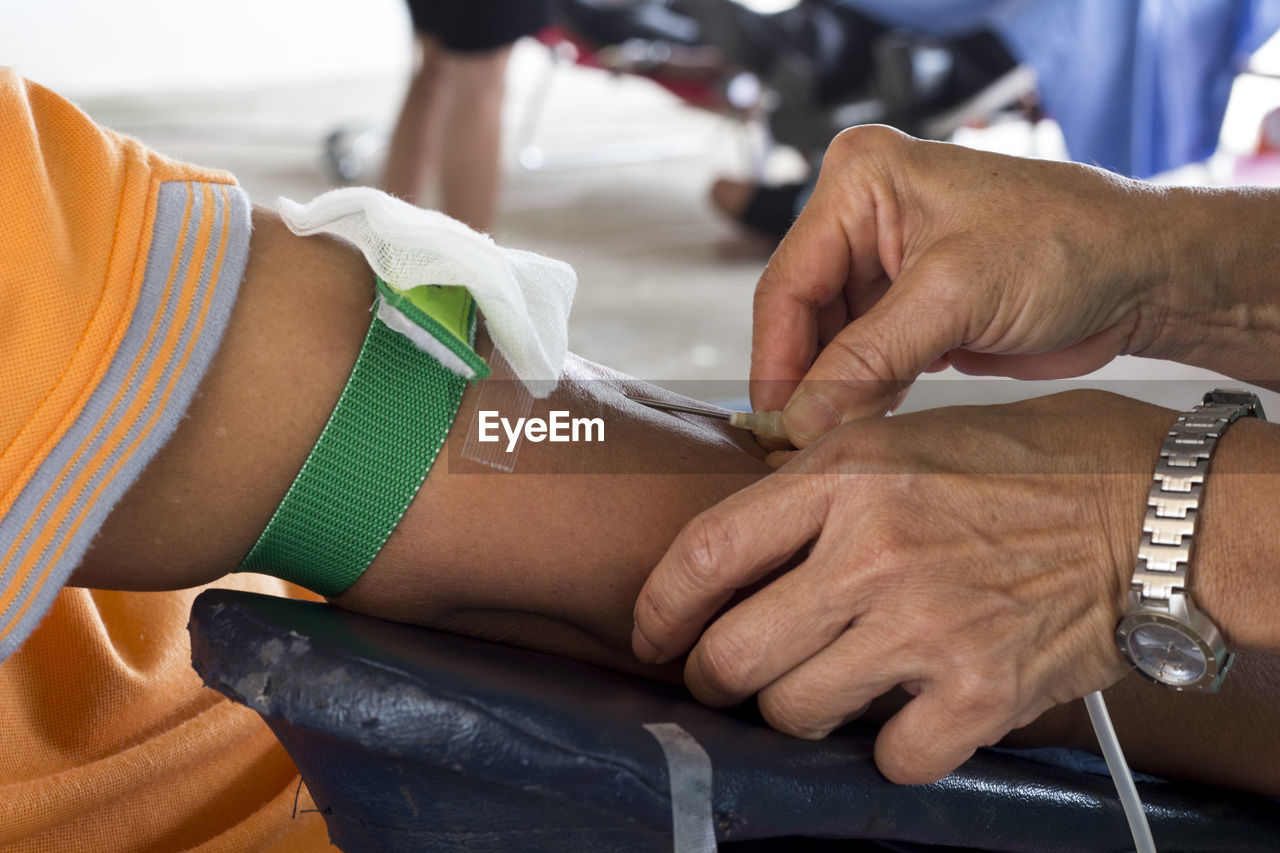 Cropped hands of doctor injecting syringe on hand of patient