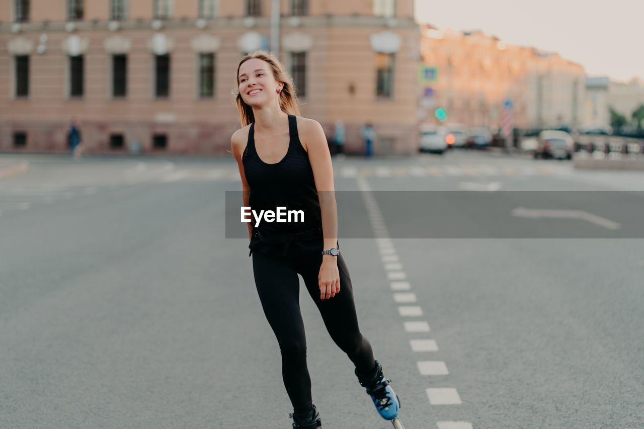 YOUNG WOMAN ON ROAD AGAINST CITY