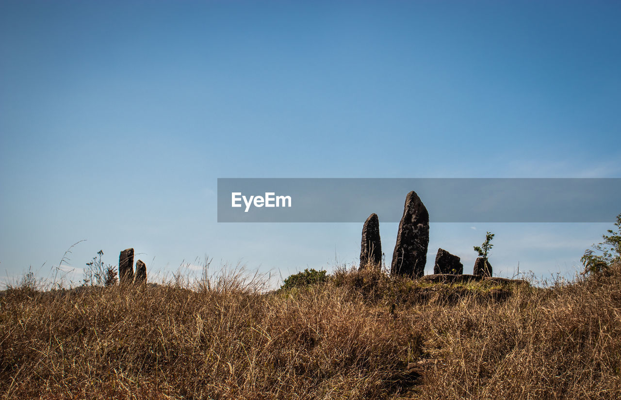 Standing sacred stone monoliths with bright blue sky and grass from a different perspective