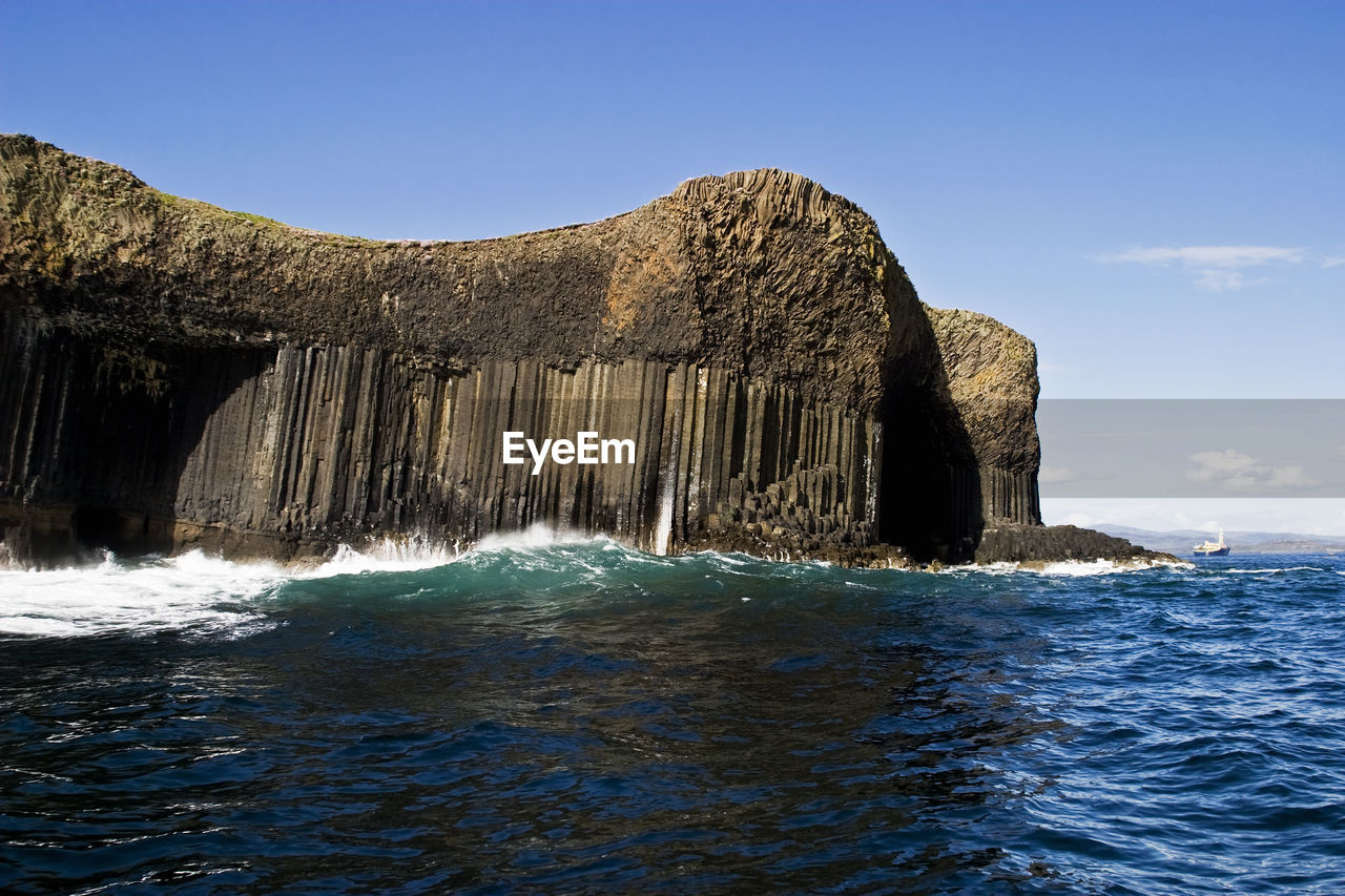 Rock formation in sea against blue sky