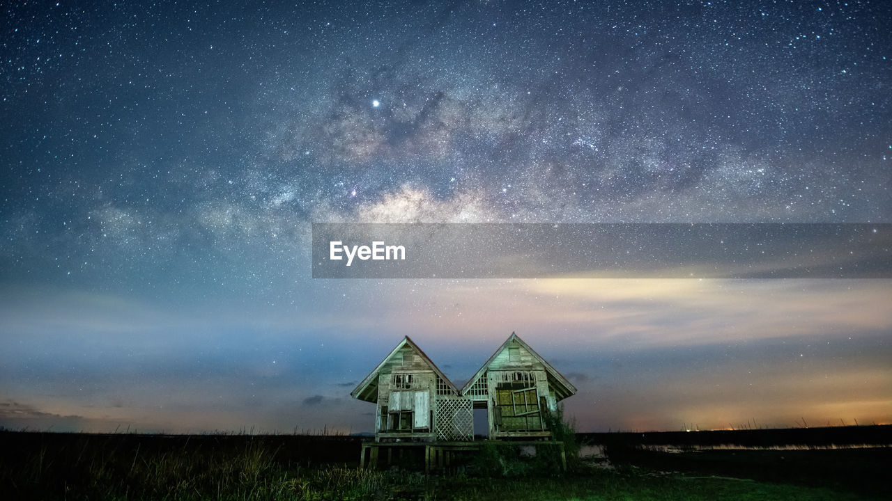 Low angle view of abandoned huts against star field in sky at night