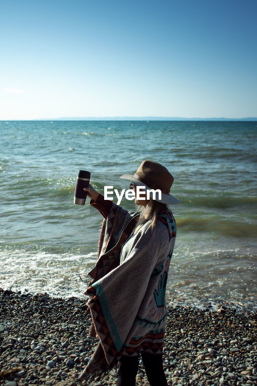 Man standing on beach against clear sky