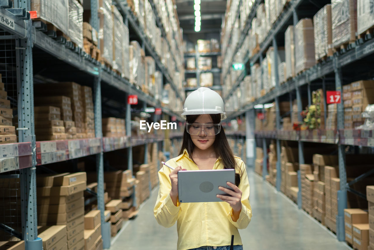 Female warehouse worker inspecting a warehouse in a factory. 