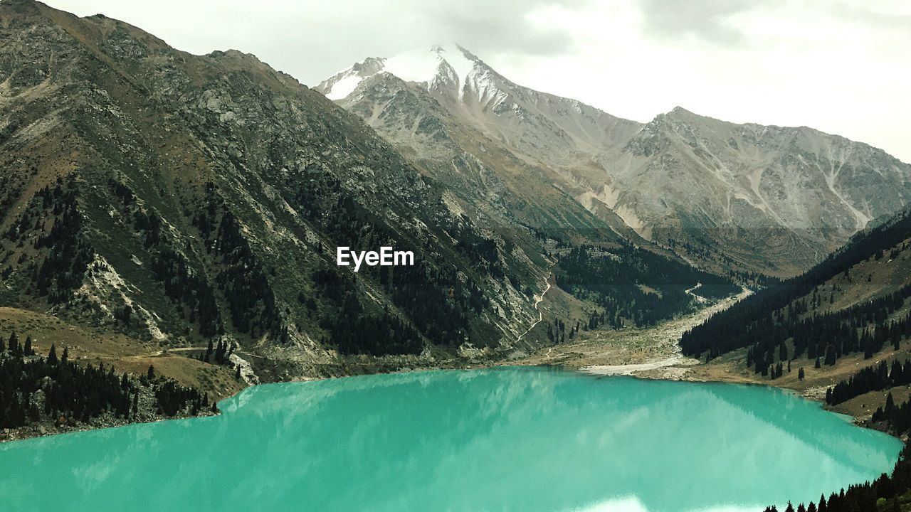 Scenic view of lake by mountains against sky