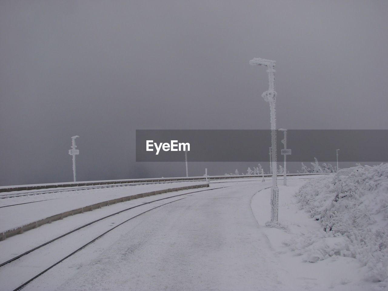 SNOW COVERED ROAD BY LAND AGAINST SKY