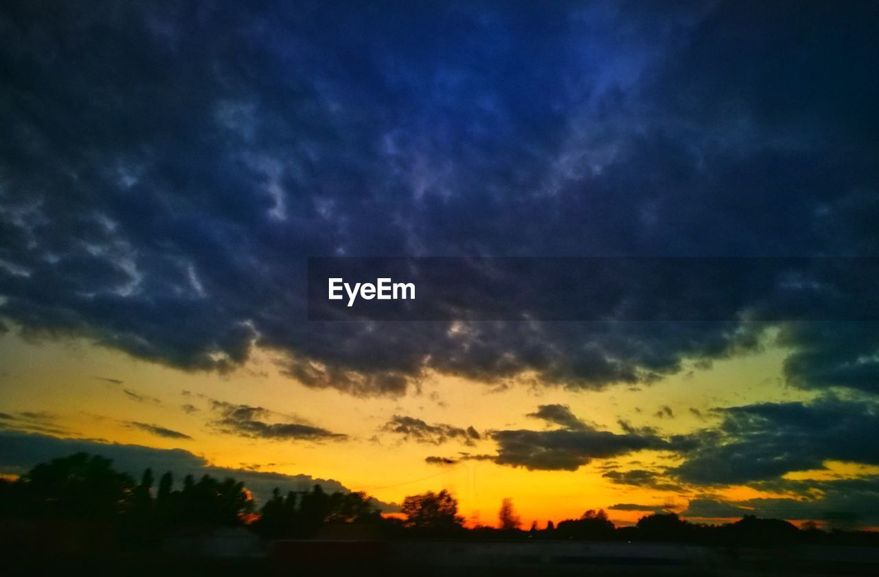 DRAMATIC SKY OVER SILHOUETTE LANDSCAPE DURING SUNSET