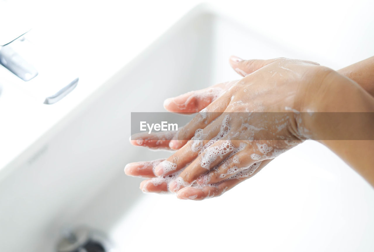 Cropped image of woman washing hands in sink at bathroom