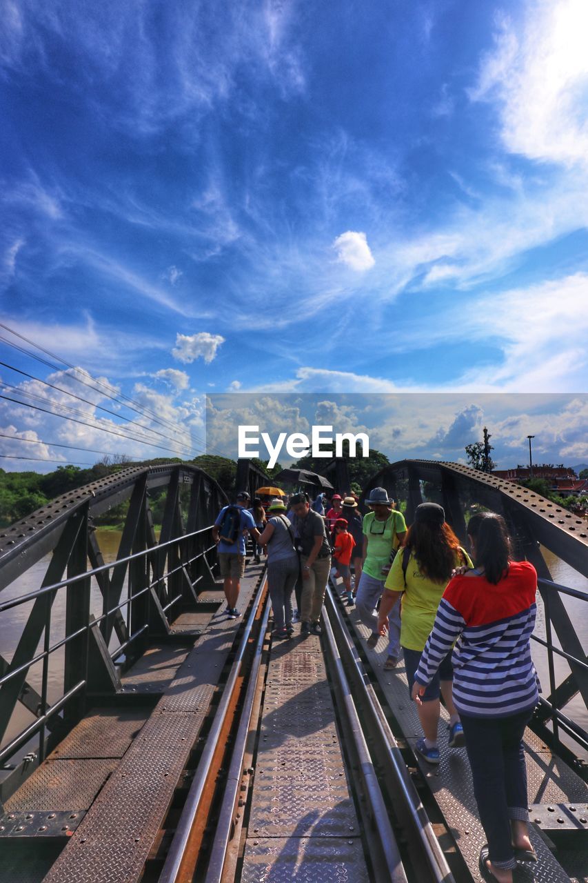 People on railway bridge against sky