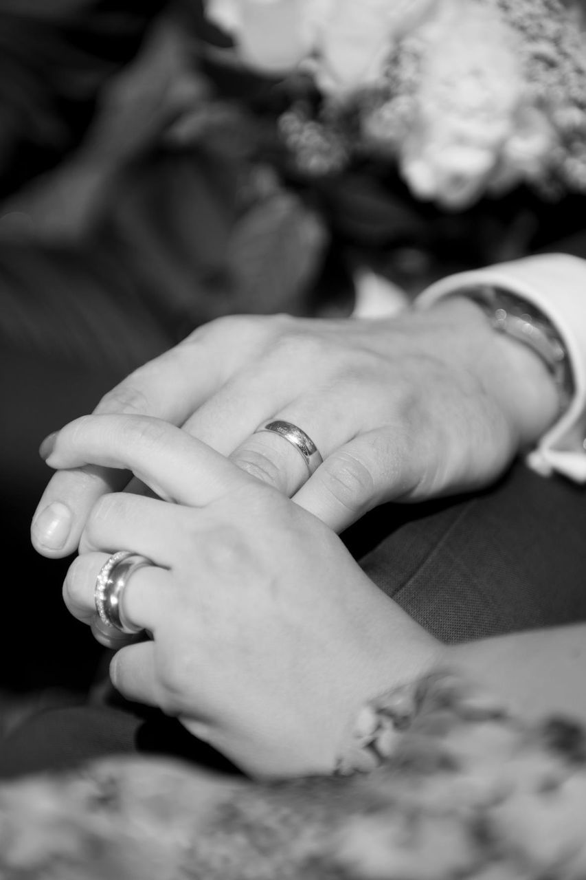 Cropped image of husband and wife holding hands during wedding
