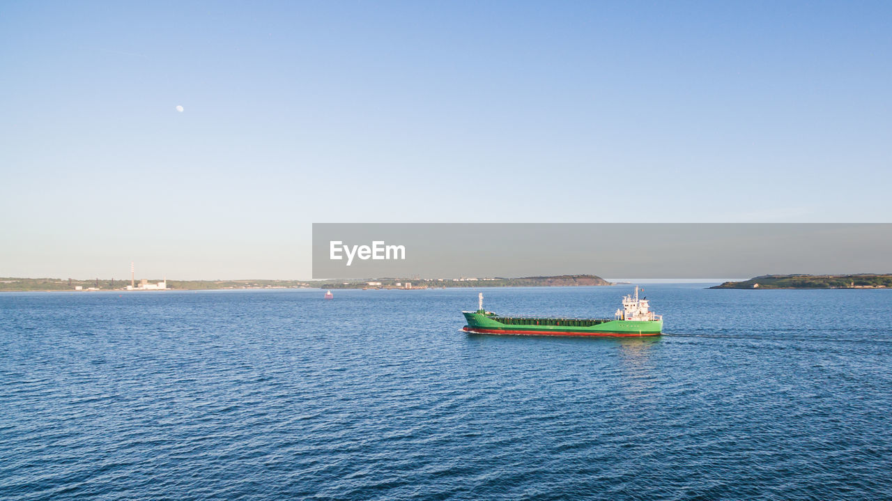 Boat sailing on sea against clear sky