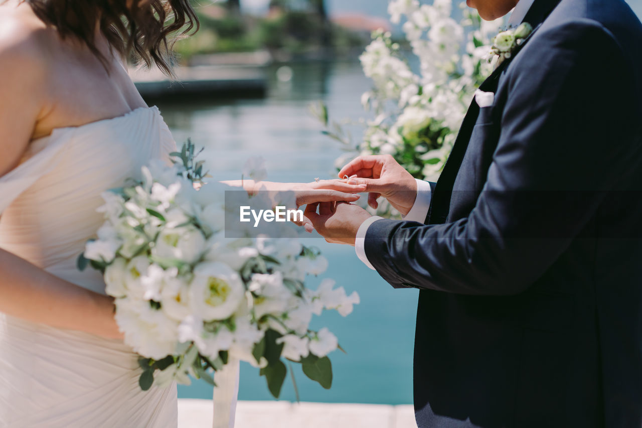 Midsection of couple holding flower bouquet