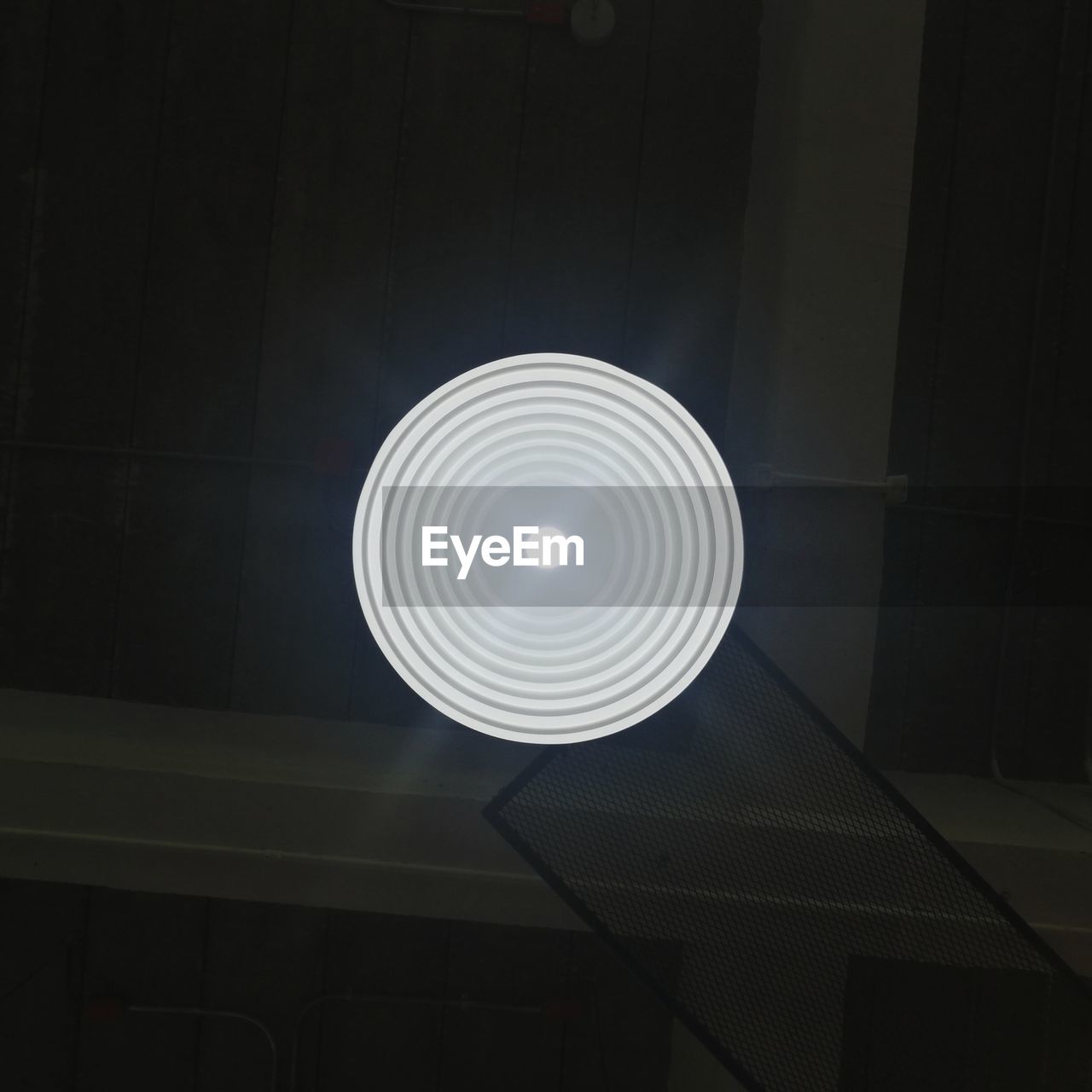 LOW ANGLE VIEW OF ILLUMINATED LAMP AGAINST DARK WALL