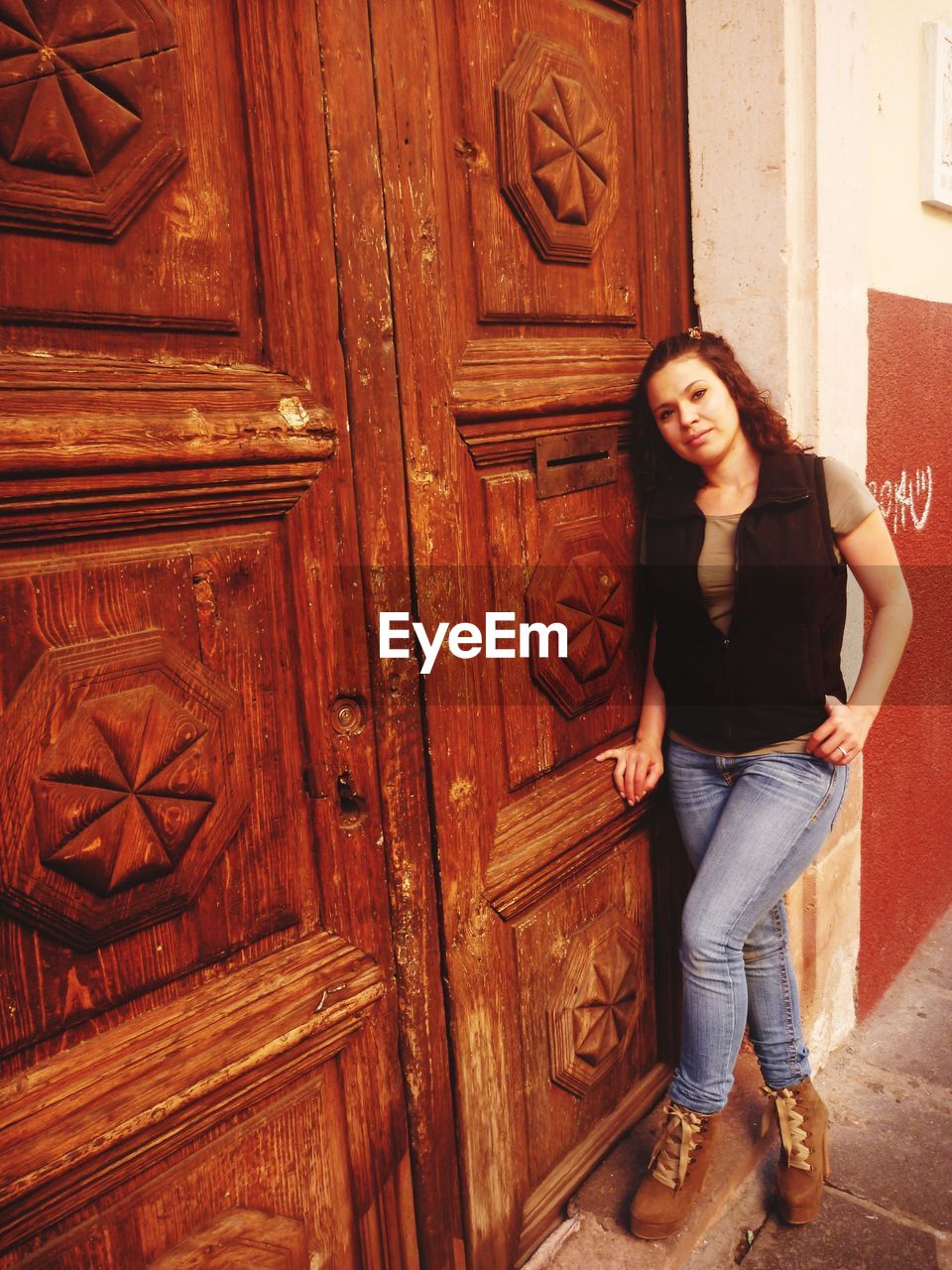 PORTRAIT OF WOMAN STANDING AT ENTRANCE OF CLOSED DOOR