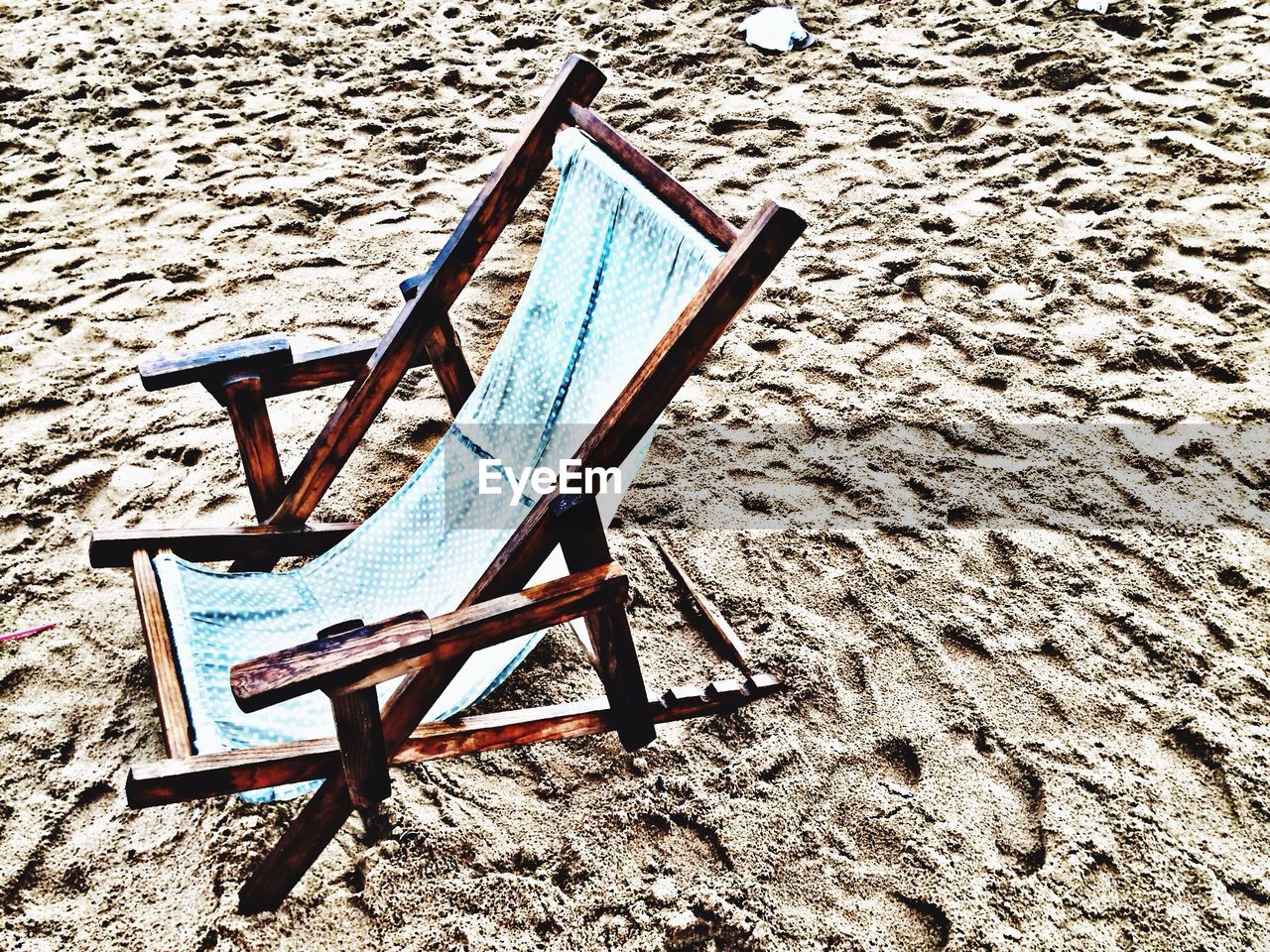 High angle view of empty deck chair on sand