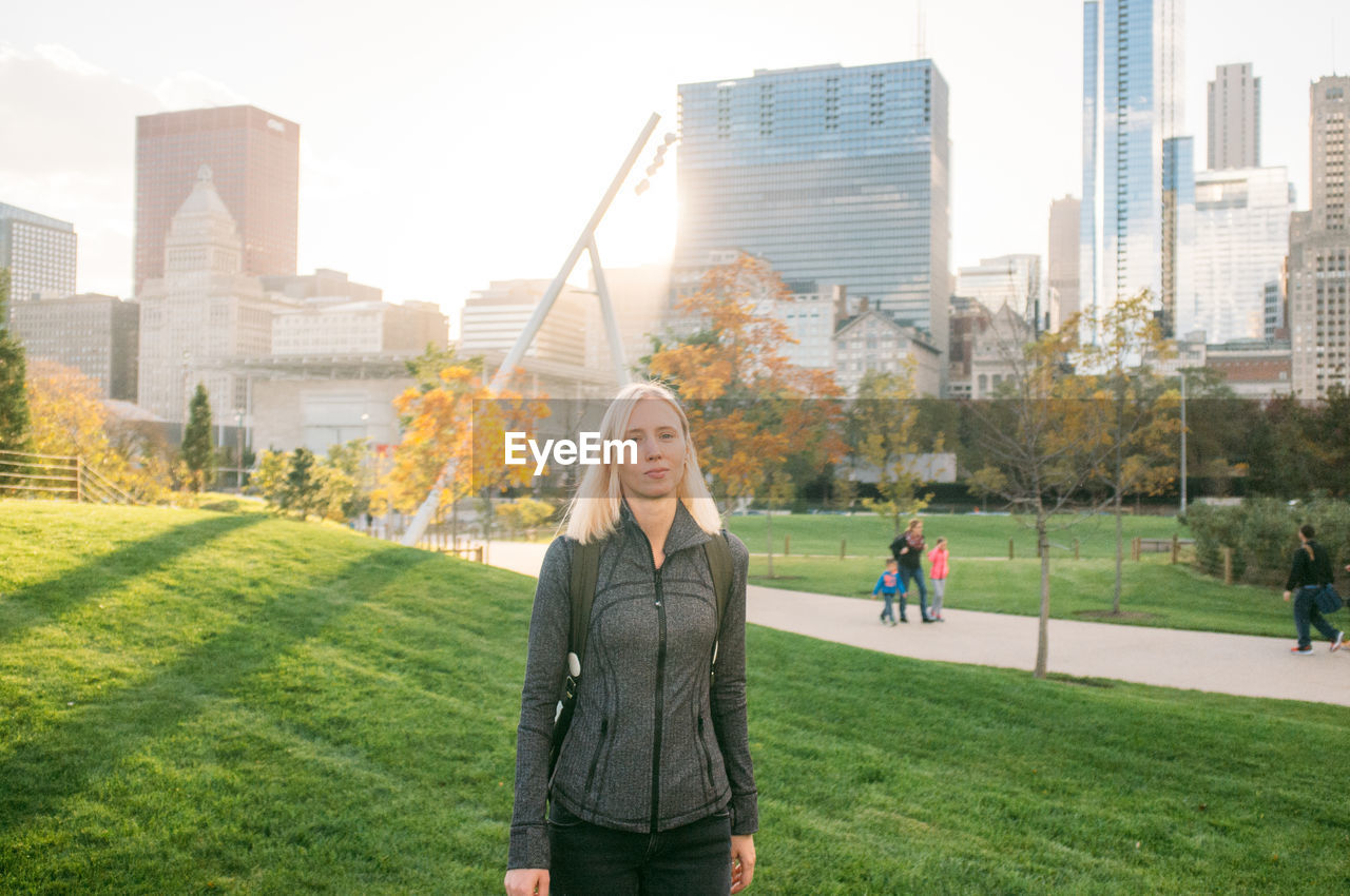 Portrait of woman at millennium park against modern buildings in city