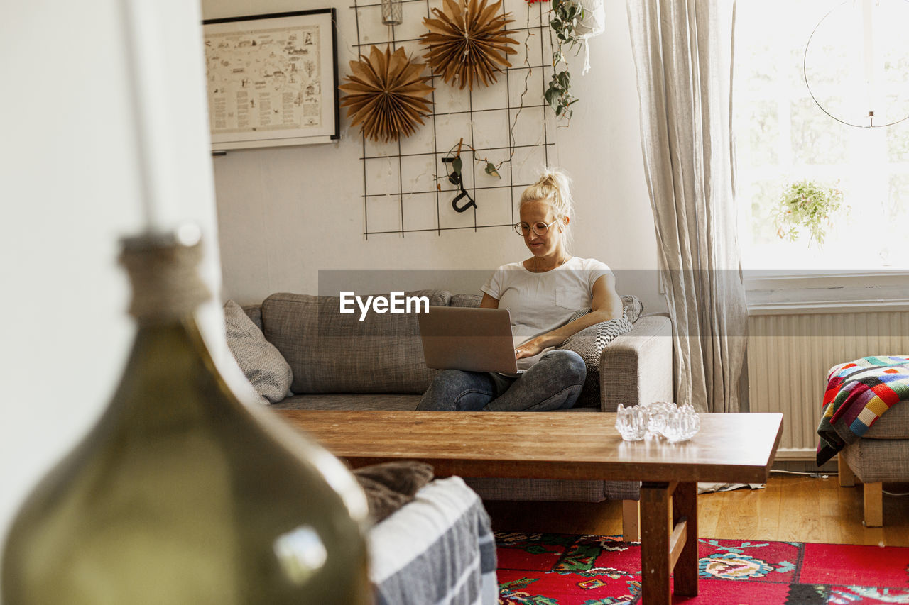 Smiling woman using laptop on sofa