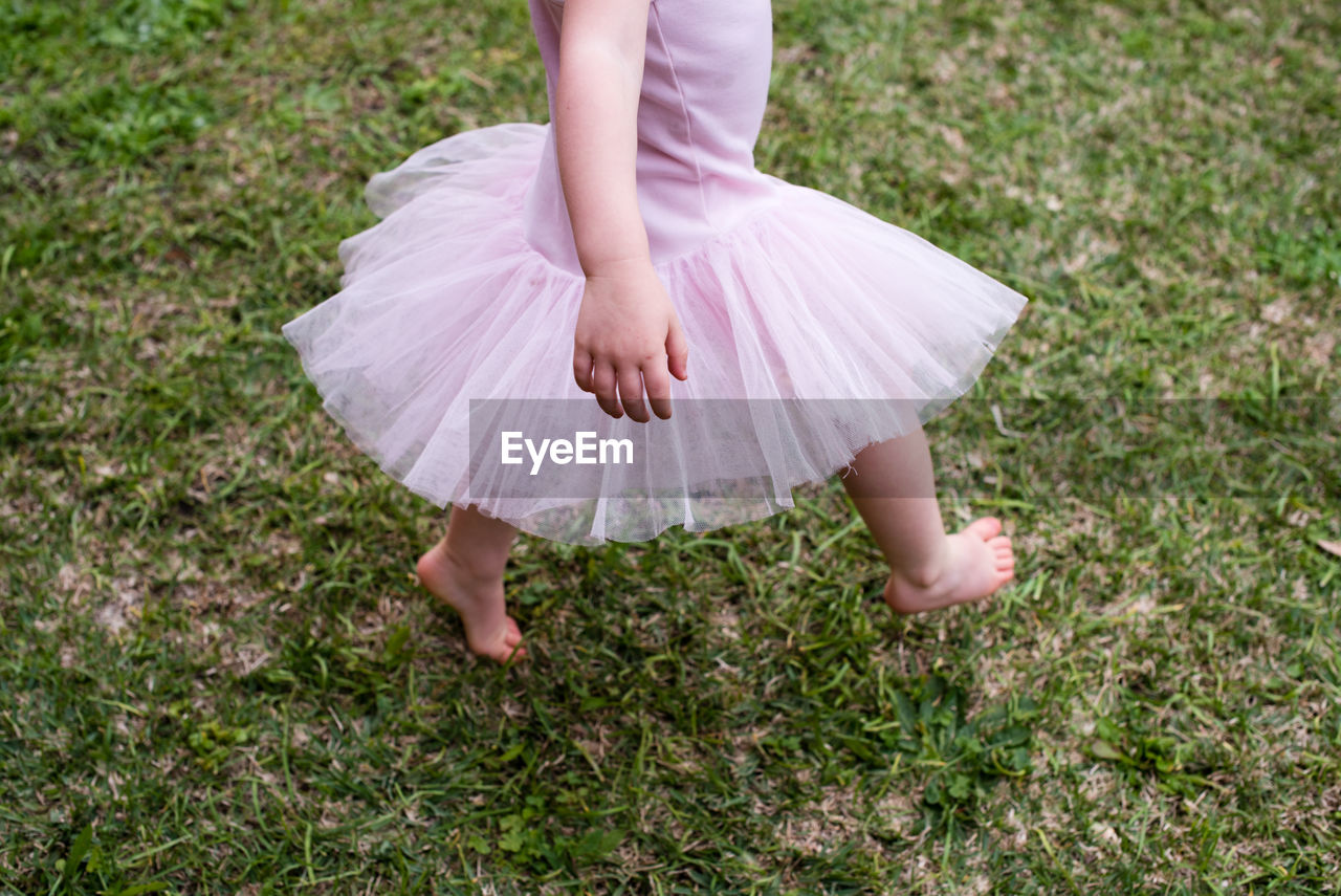 Low section of girl walking on field