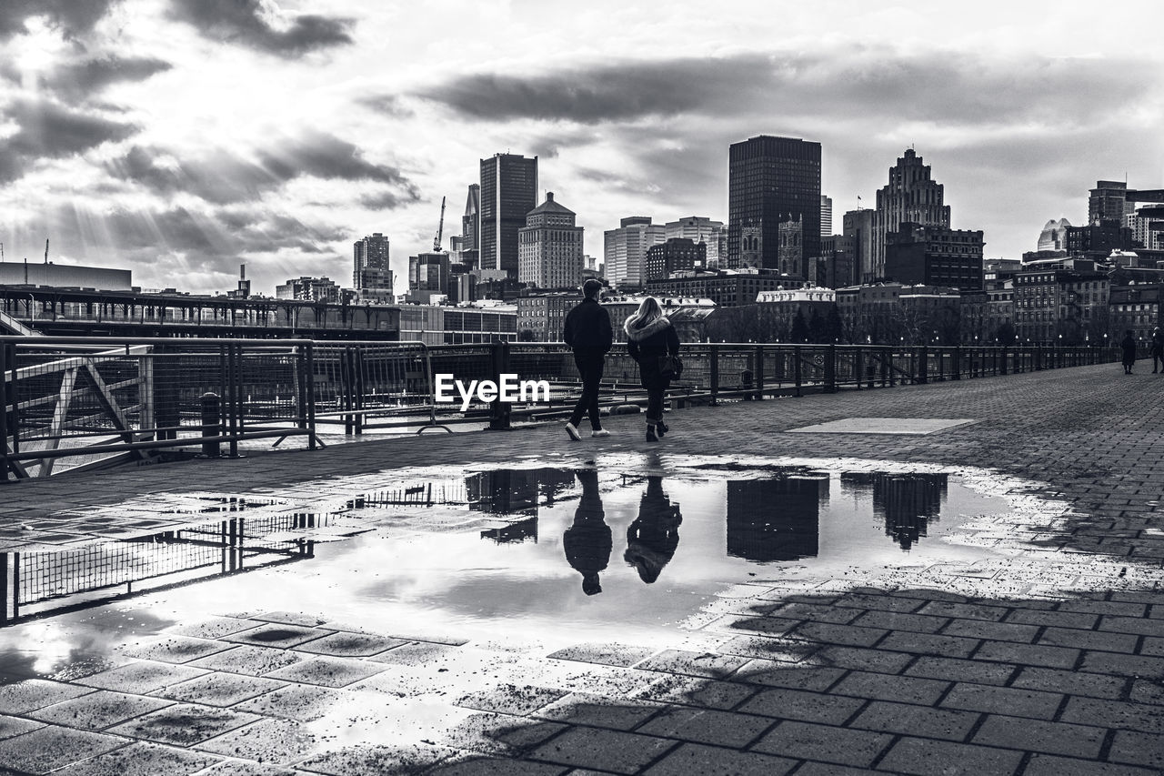 Man standing by buildings in city against sky