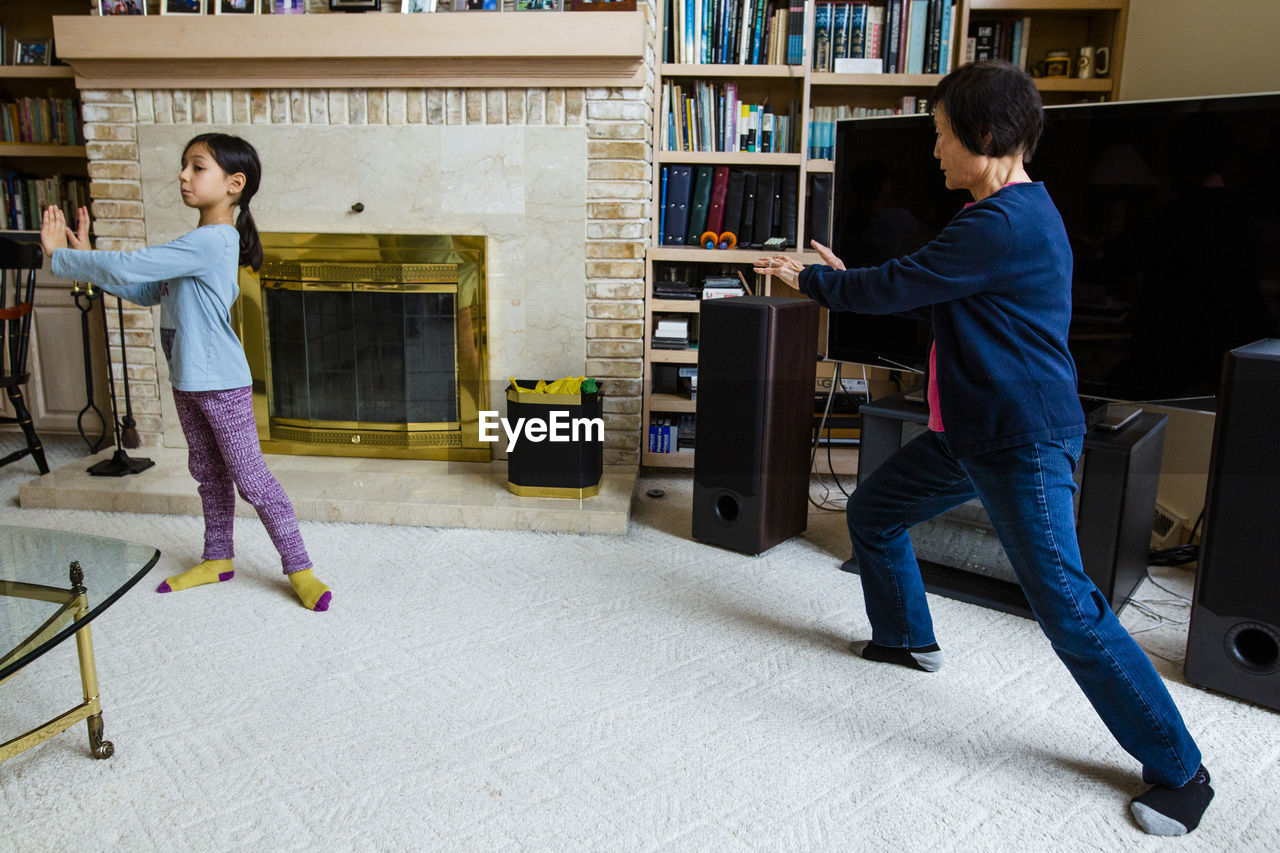 Asian grandmother teaching granddaughter tai-chi at home