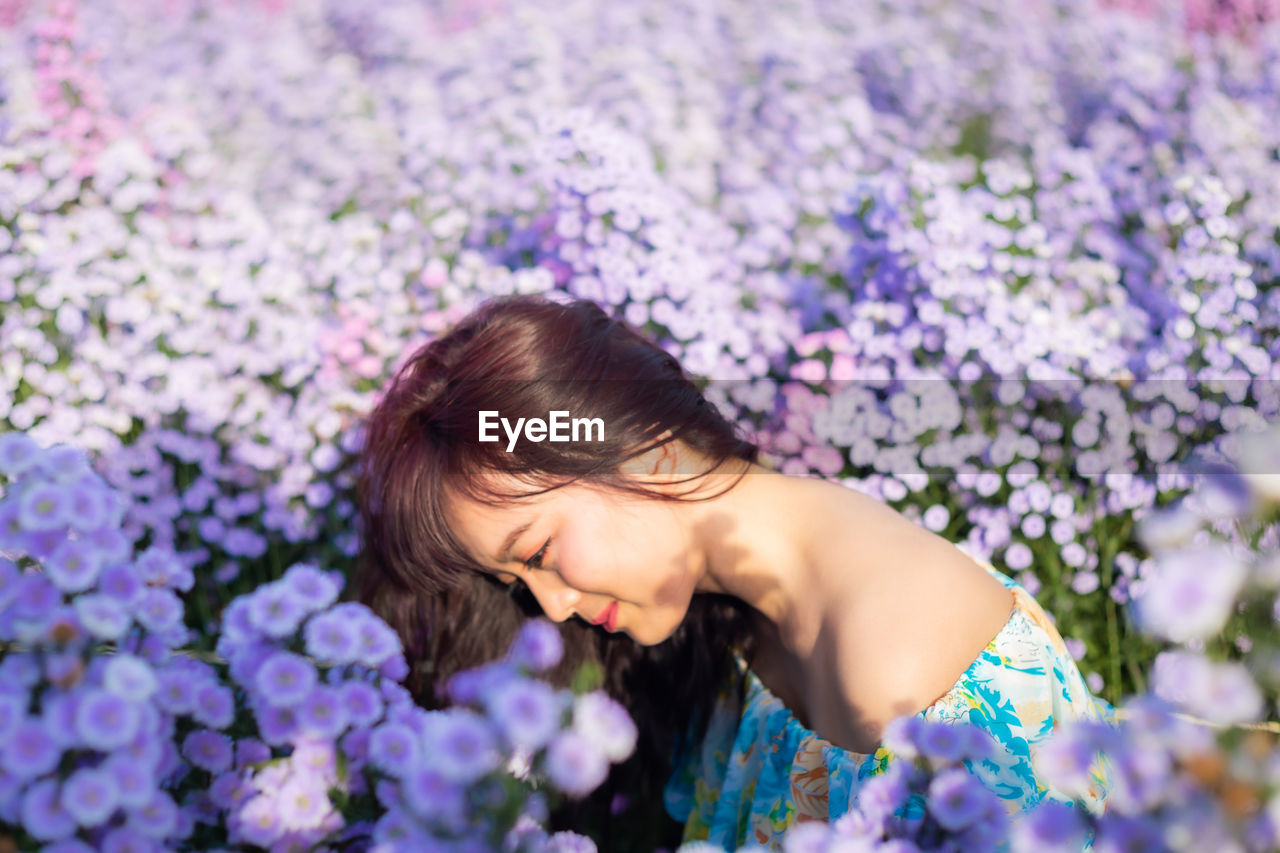 HIGH ANGLE VIEW OF WOMAN AND PURPLE FLOWER