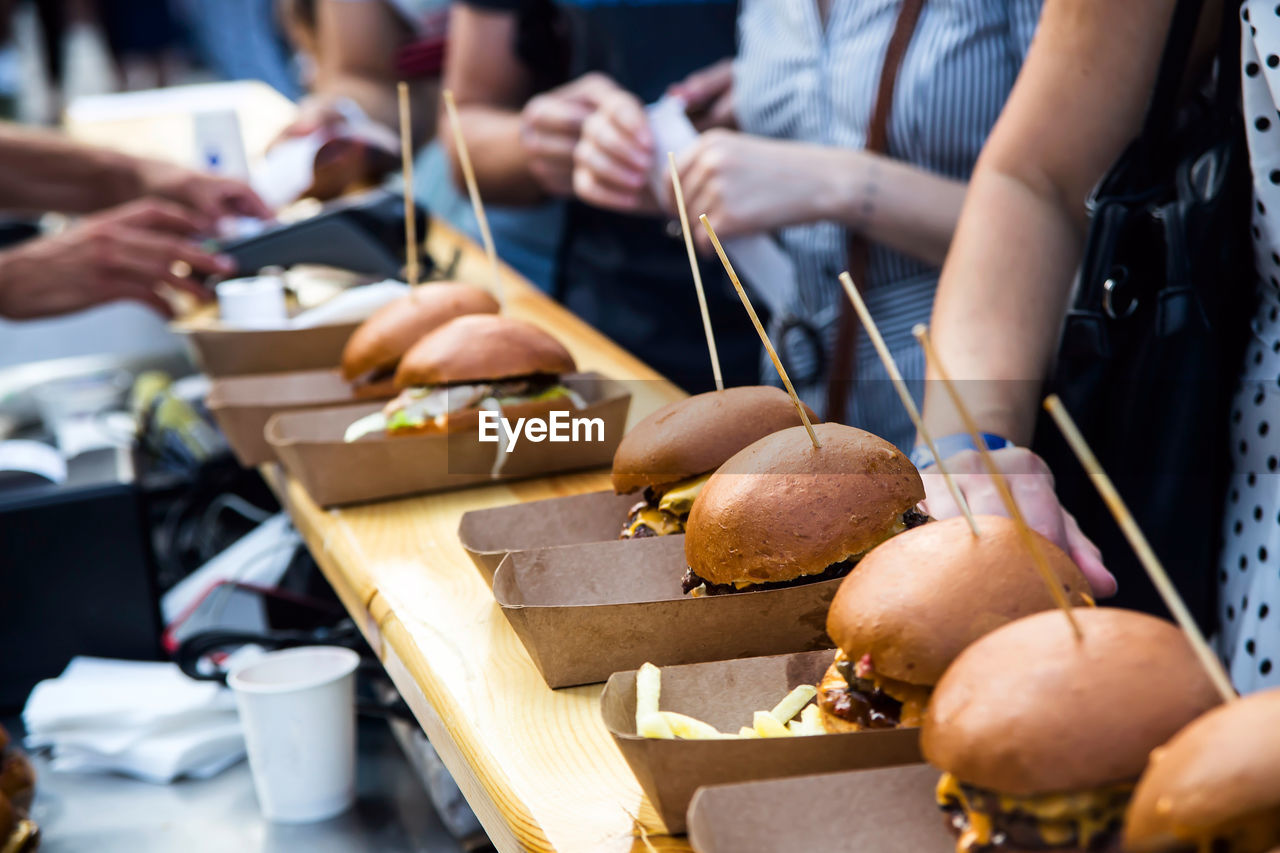 Street food many burgers with meat and cheese and french fries in craft packaging. 