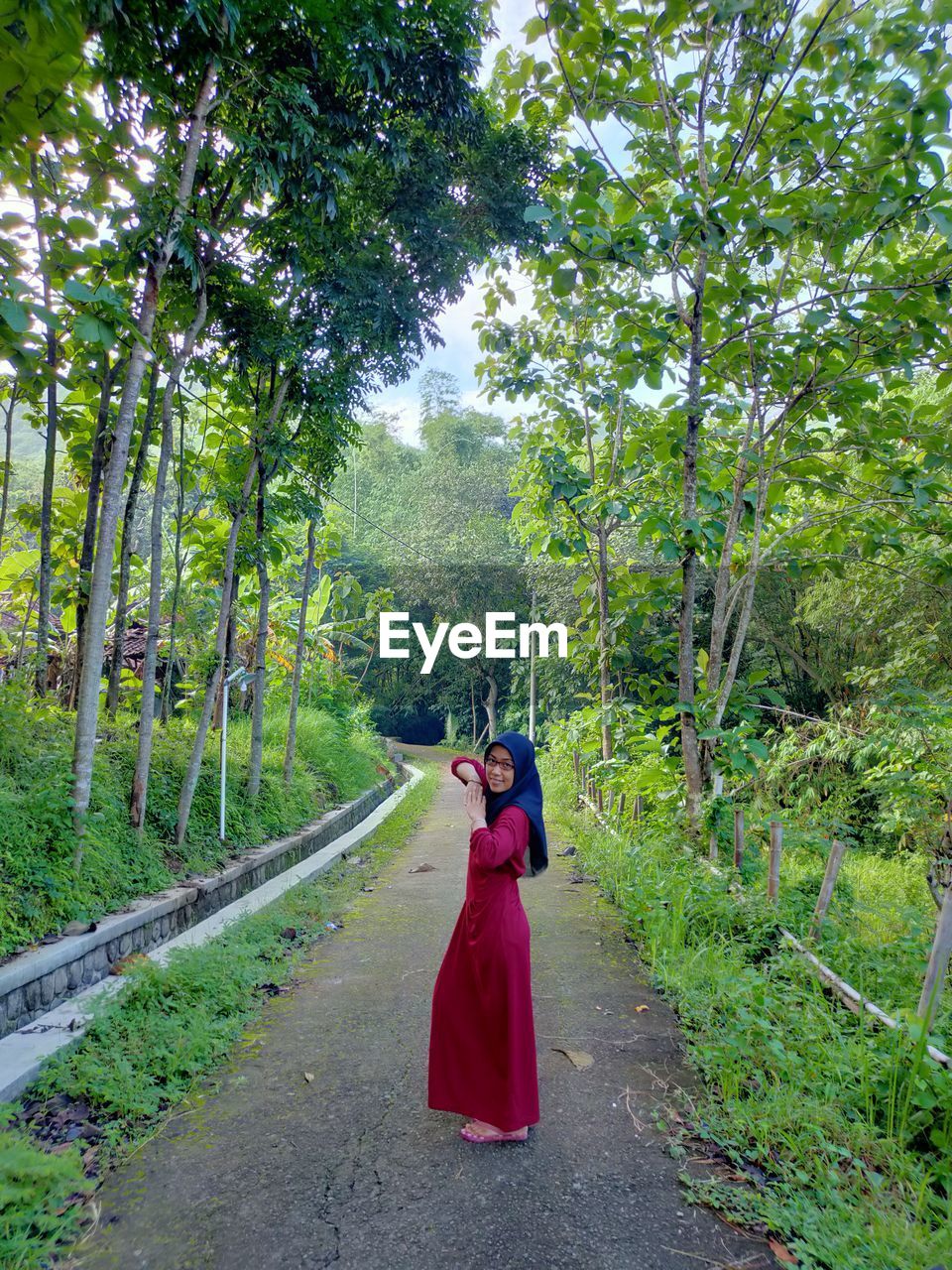 Woman standing on road amidst trees