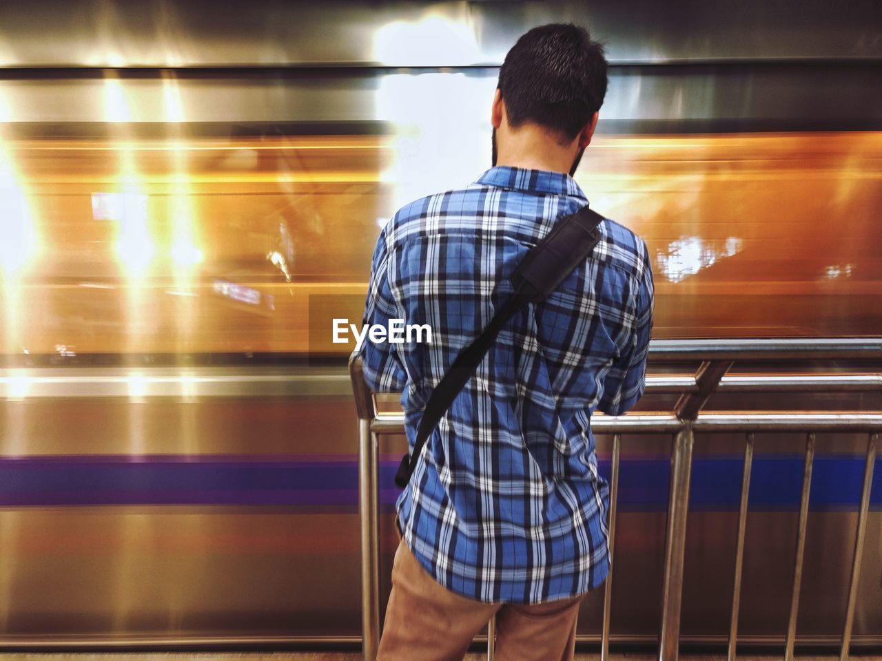 Rear view of man standing at railroad station