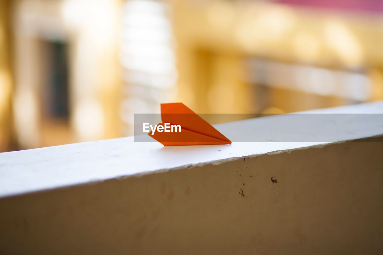 Close-up of paper airplane on retaining wall