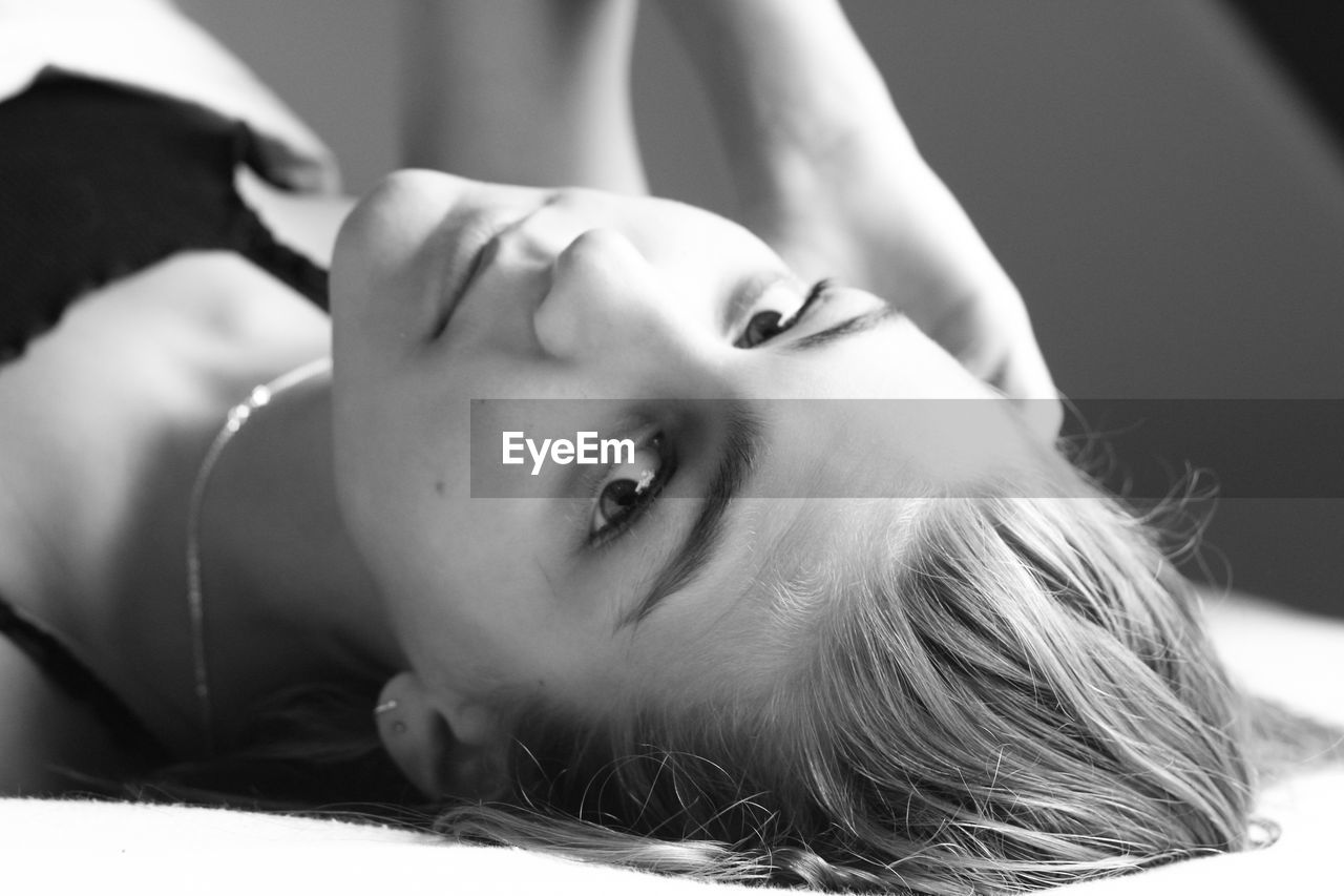 Close-up portrait of young woman lying on bed