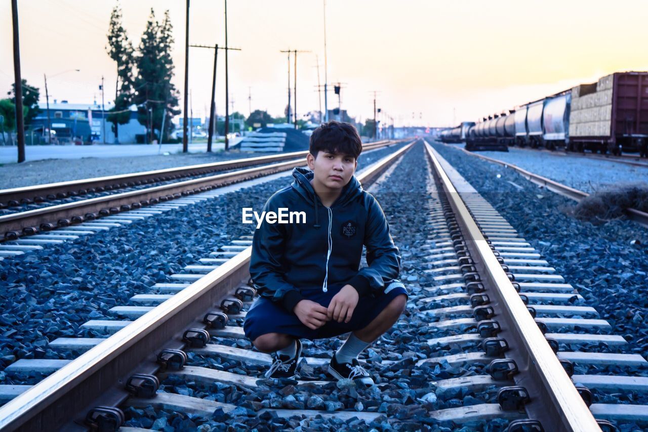 MAN SITTING ON RAILROAD TRACKS