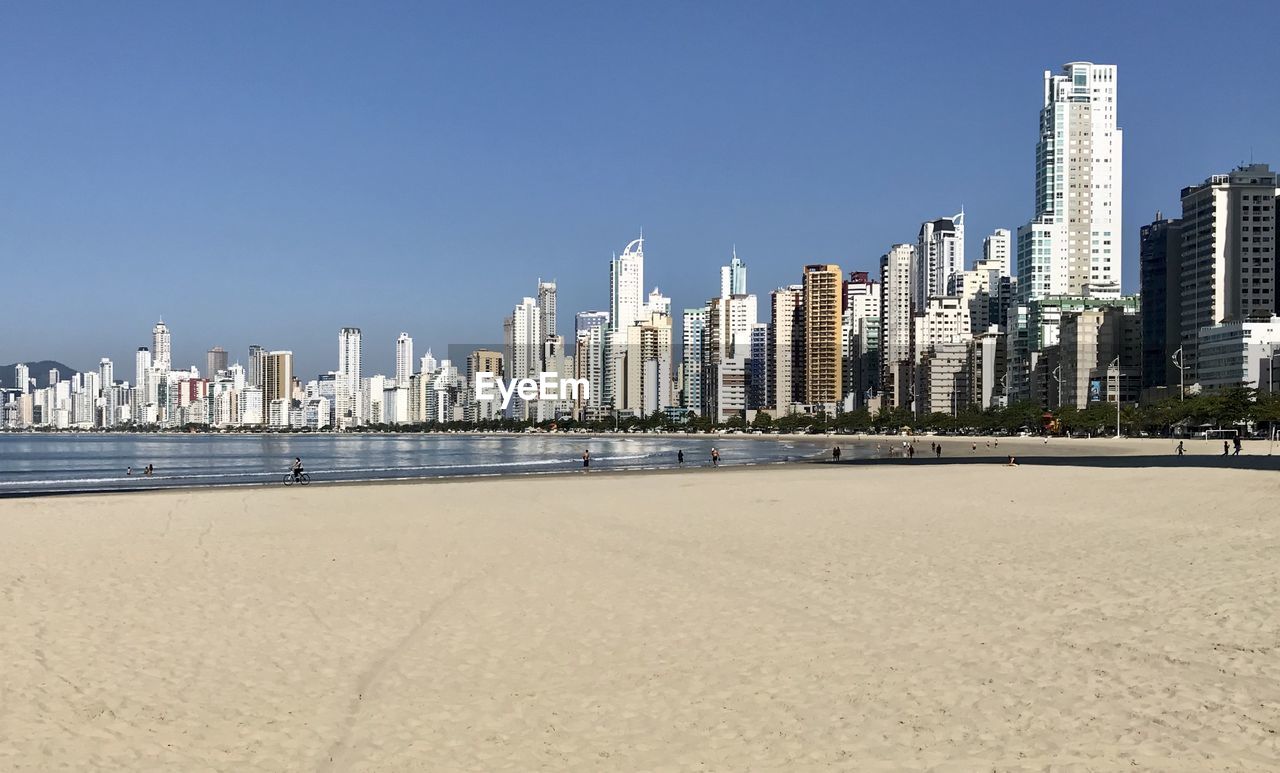 Sea by modern buildings against clear sky