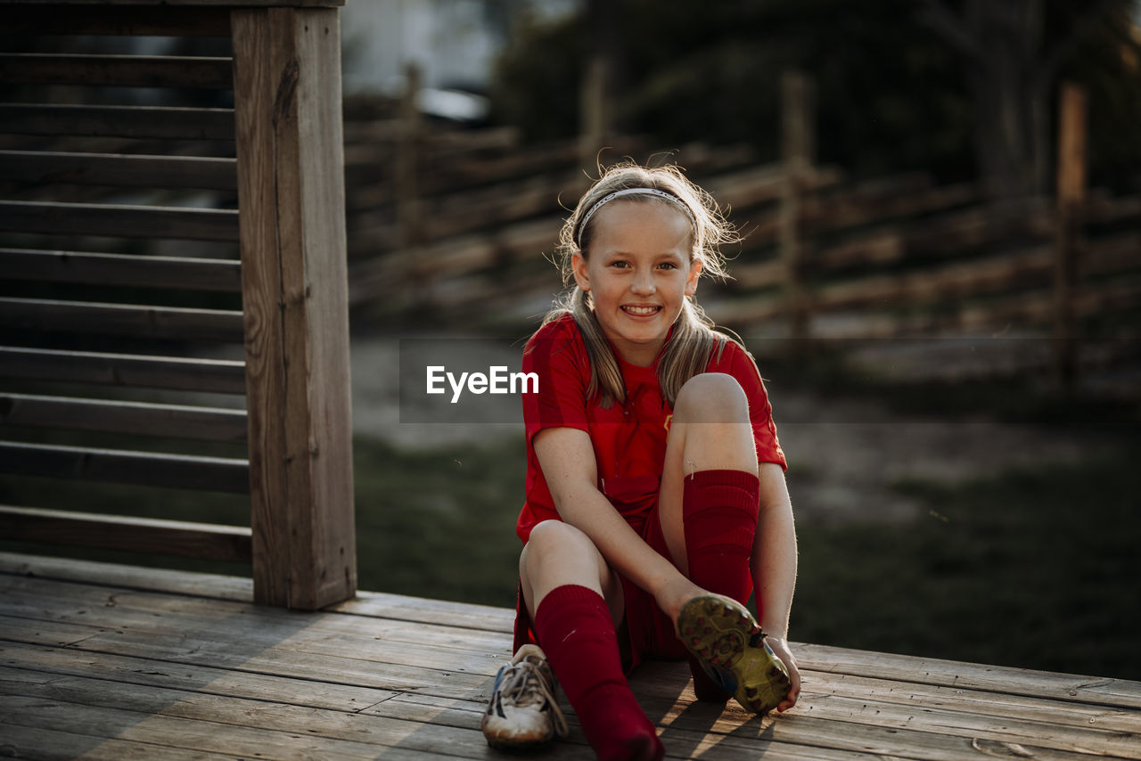 Smiling girl putting football shoes on