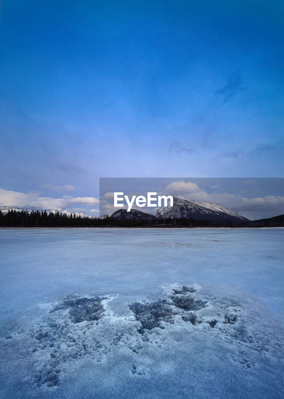 Scenic view of frozen lake against blue sky