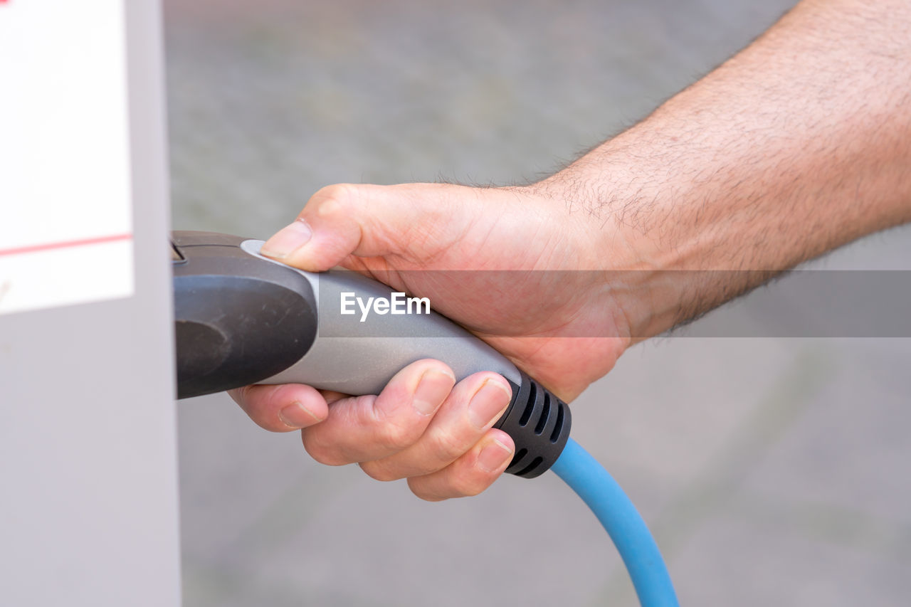 Man hand holding an electric vehicle charging connector